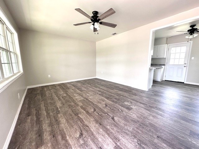 unfurnished room featuring a ceiling fan, baseboards, visible vents, and dark wood-style floors