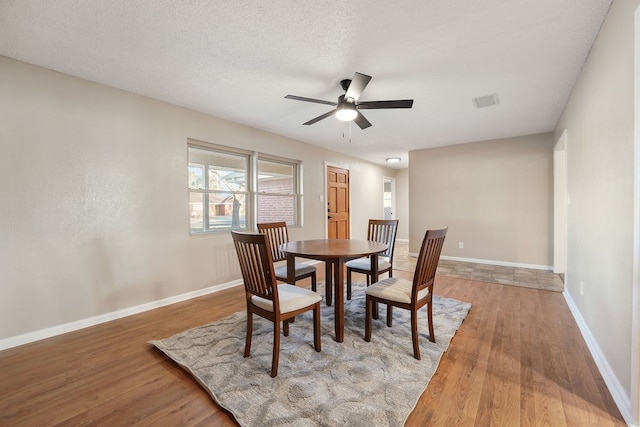 dining area featuring ceiling fan, wood-type flooring, and a textured ceiling