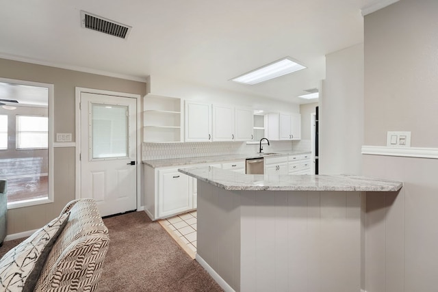 kitchen with white cabinets, dishwasher, light stone countertops, and kitchen peninsula