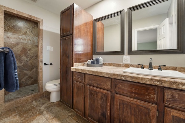 bathroom featuring vanity, toilet, and a tile shower