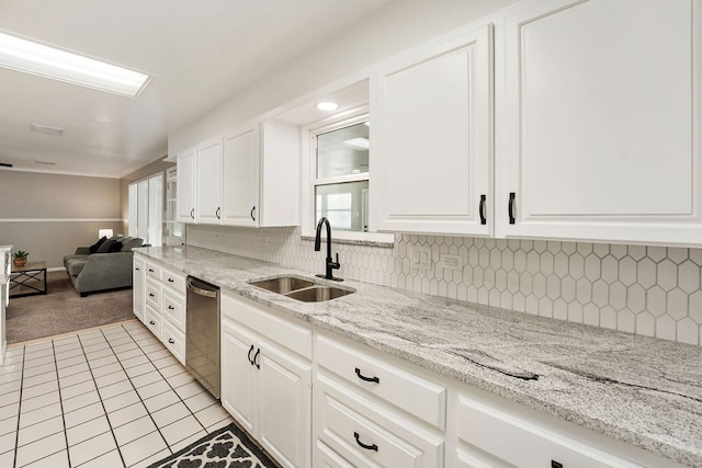 kitchen featuring white cabinets, stainless steel dishwasher, light stone countertops, and sink