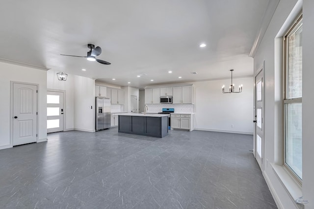 kitchen featuring a kitchen island, ceiling fan with notable chandelier, decorative light fixtures, tasteful backsplash, and stainless steel appliances