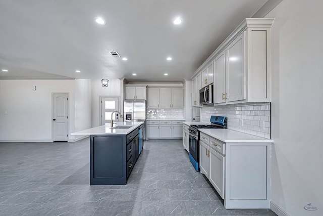 kitchen featuring appliances with stainless steel finishes, sink, a kitchen island with sink, and backsplash