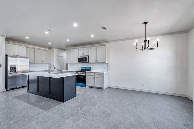 kitchen with sink, tasteful backsplash, decorative light fixtures, appliances with stainless steel finishes, and a kitchen island with sink