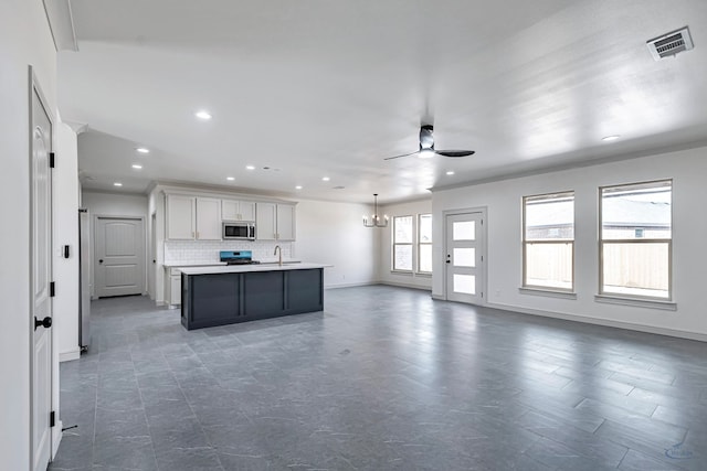 kitchen with backsplash, an island with sink, pendant lighting, stainless steel appliances, and white cabinets