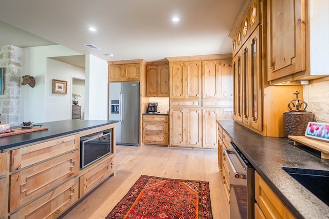 kitchen with stainless steel appliances, dark countertops, visible vents, and light wood-style floors