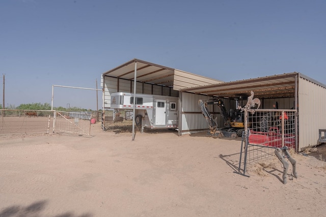 view of outdoor structure with fence and a carport