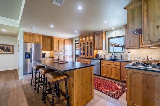 kitchen featuring dark countertops, appliances with stainless steel finishes, a breakfast bar area, a center island, and backsplash