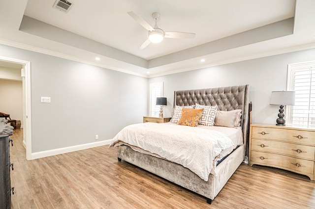 bedroom featuring ceiling fan, ornamental molding, a raised ceiling, and hardwood / wood-style floors