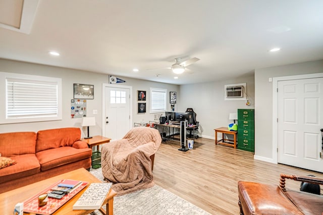 living room featuring a wall unit AC, light hardwood / wood-style floors, and ceiling fan