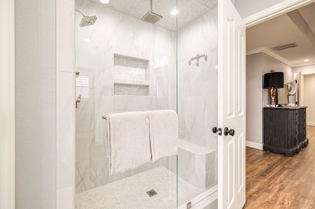 bathroom featuring hardwood / wood-style flooring, crown molding, and a tile shower