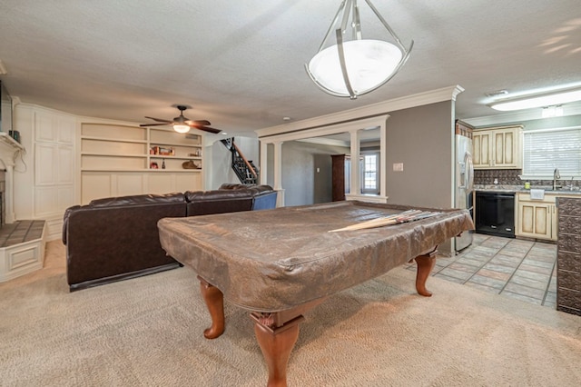 recreation room featuring light carpet, crown molding, ceiling fan, sink, and a textured ceiling