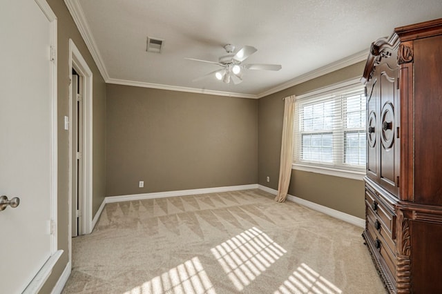 spare room with ceiling fan, ornamental molding, and light carpet