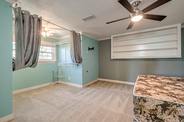 interior space with light carpet, ceiling fan, ornamental molding, and a textured ceiling