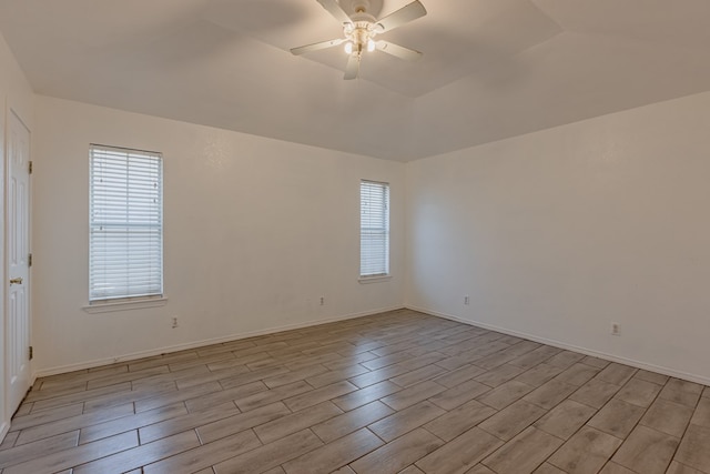 unfurnished room with a wealth of natural light, a raised ceiling, and ceiling fan