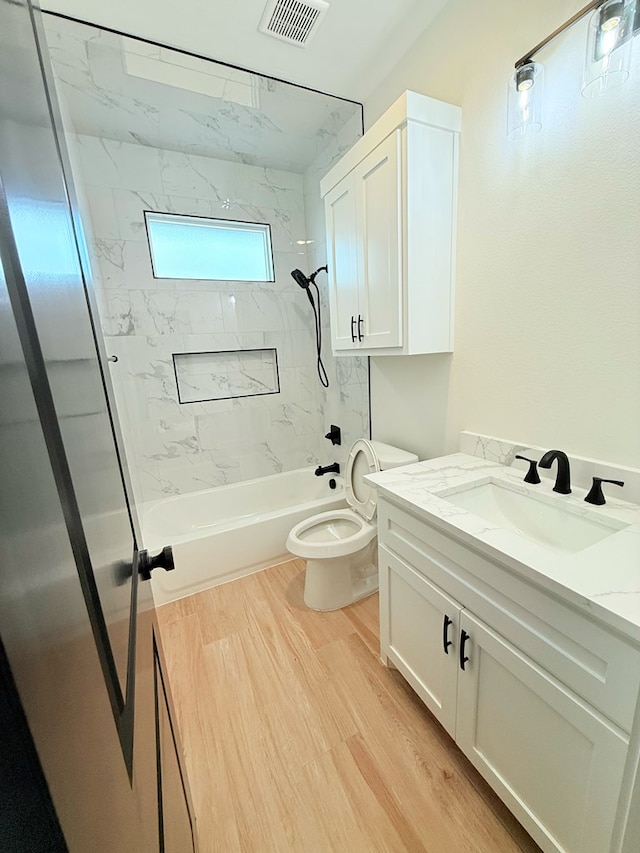 full bathroom with wood-type flooring, vanity, toilet, and tiled shower / bath