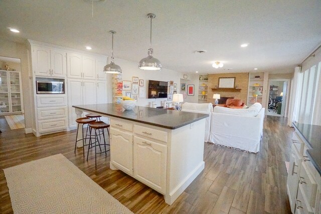 5 Bristol Ct, Midland, TX 79705 - kitchen featuring dark countertops, a center island, white cabinets, stainless steel microwave, and dark wood-type flooring