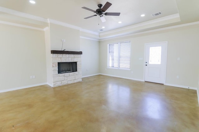 unfurnished living room featuring ornamental molding, a tray ceiling, ceiling fan, concrete floors, and a stone fireplace