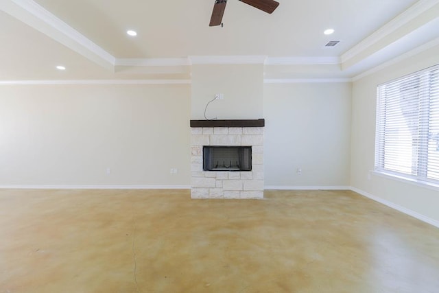 unfurnished living room with a tray ceiling, a stone fireplace, ceiling fan, and ornamental molding