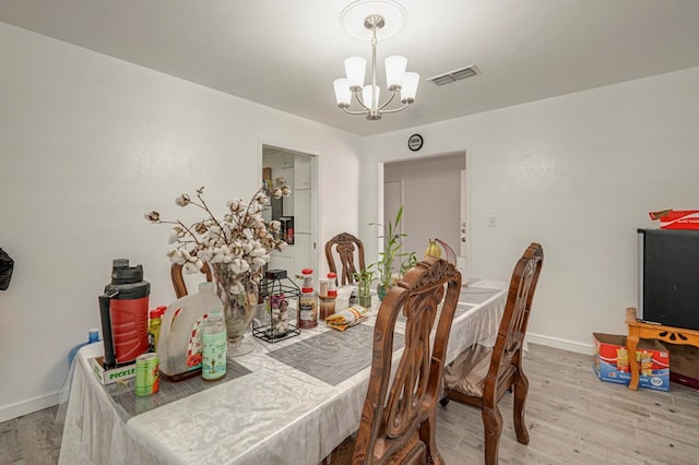 dining area with light wood-type flooring and a chandelier