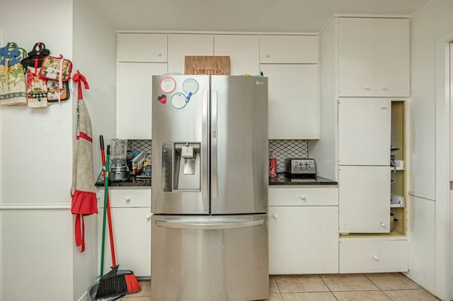 kitchen with white cabinets, light tile patterned flooring, and stainless steel fridge