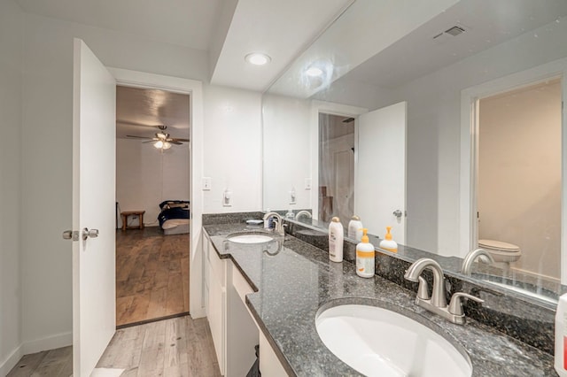 bathroom featuring vanity, wood-type flooring, toilet, and ceiling fan