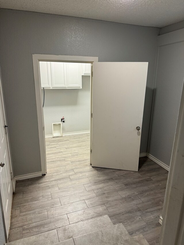 washroom with light wood-type flooring and a textured ceiling