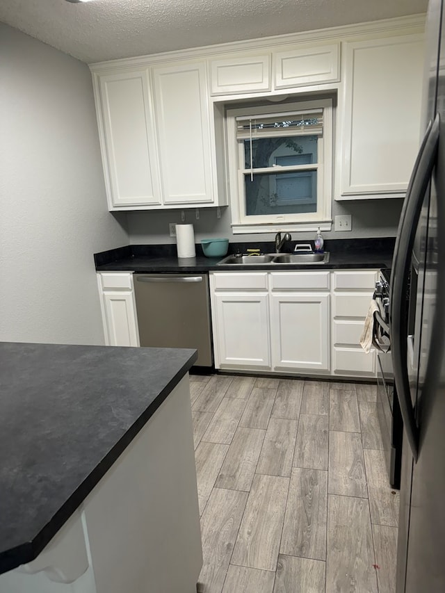 kitchen with sink, stainless steel appliances, light hardwood / wood-style flooring, a textured ceiling, and white cabinets