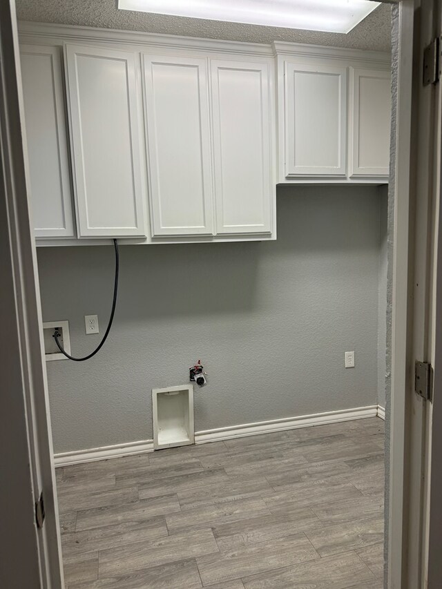 laundry area featuring cabinets, hookup for a washing machine, light wood-type flooring, and a textured ceiling