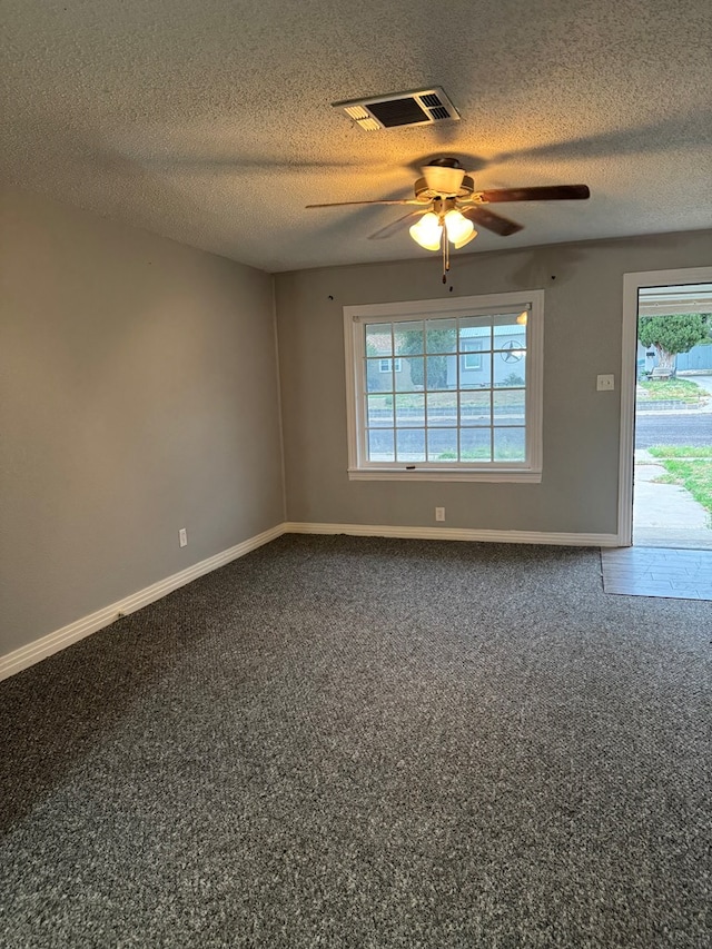 carpeted spare room with ceiling fan, a textured ceiling, and a wealth of natural light