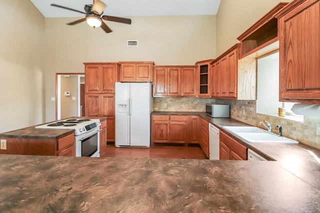 kitchen with backsplash, white appliances, sink, and a towering ceiling