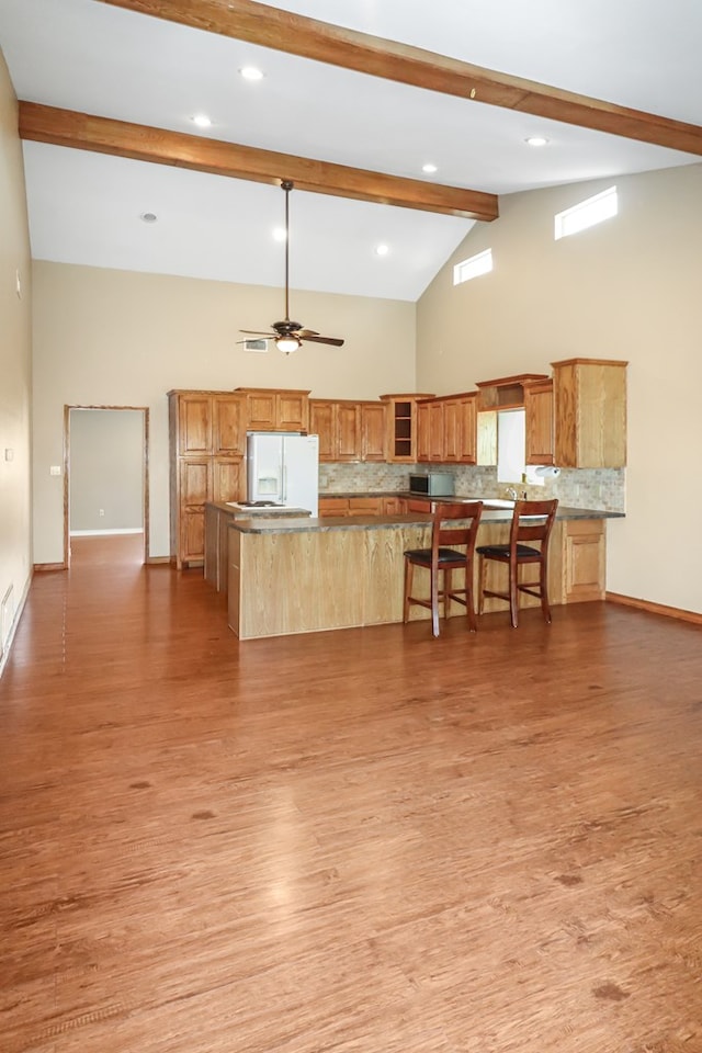 kitchen featuring a kitchen island, ceiling fan, white refrigerator with ice dispenser, light hardwood / wood-style floors, and backsplash