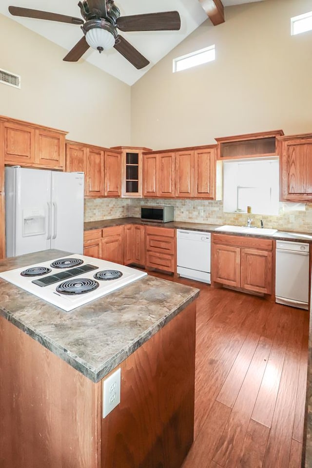 kitchen featuring white appliances, high vaulted ceiling, tasteful backsplash, light stone countertops, and light hardwood / wood-style floors