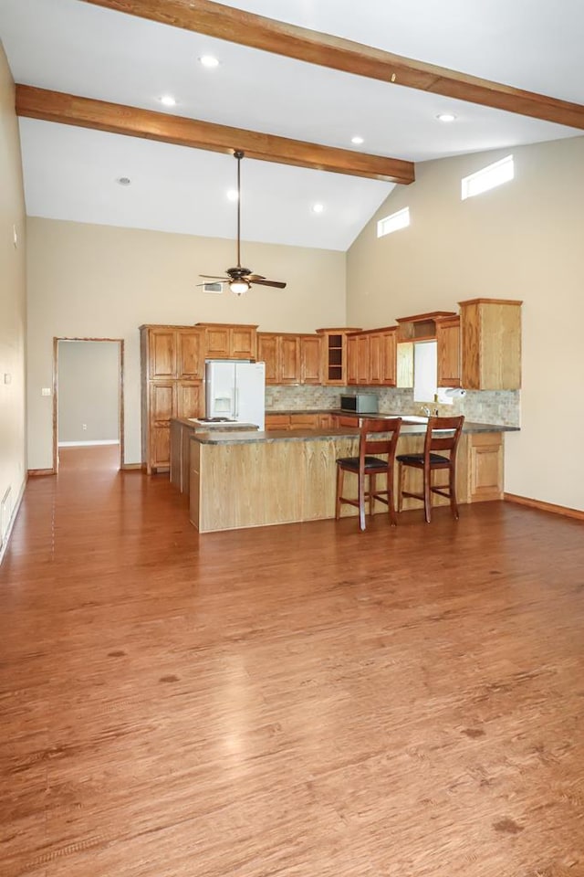 kitchen with a center island, light hardwood / wood-style flooring, white fridge with ice dispenser, ceiling fan, and backsplash