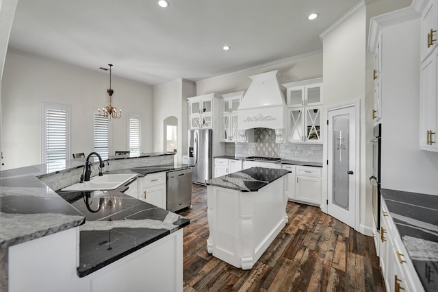 kitchen with a spacious island, custom range hood, a notable chandelier, stainless steel appliances, and a sink