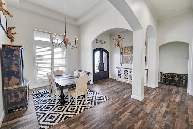 dining space featuring wood finished floors, baseboards, arched walkways, and a chandelier