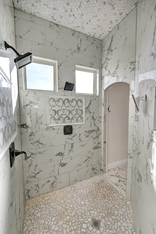 full bath with tiled shower and marble finish floor