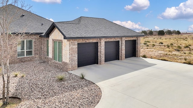 view of property exterior with concrete driveway, an attached garage, brick siding, and roof with shingles