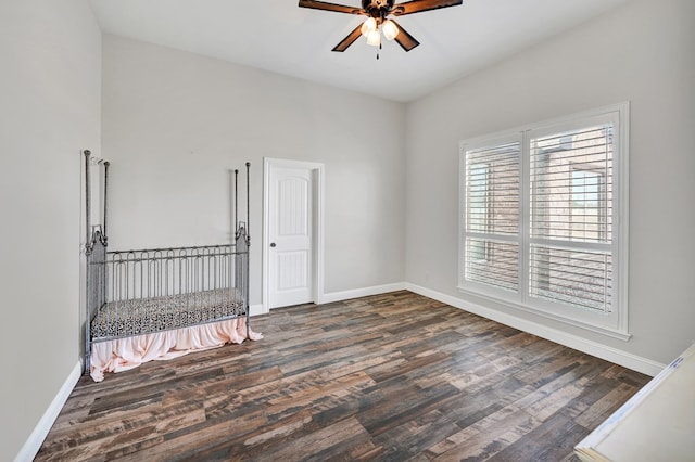 spare room with dark wood finished floors, baseboards, and a ceiling fan