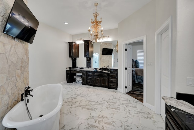 ensuite bathroom with baseboards, a soaking tub, double vanity, a notable chandelier, and marble finish floor