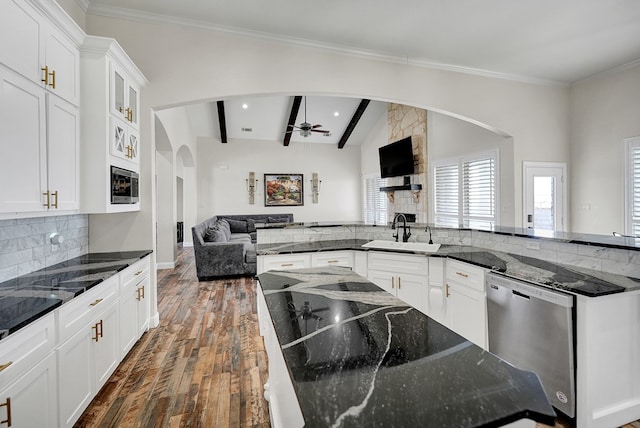 kitchen featuring tasteful backsplash, open floor plan, arched walkways, stainless steel appliances, and a sink