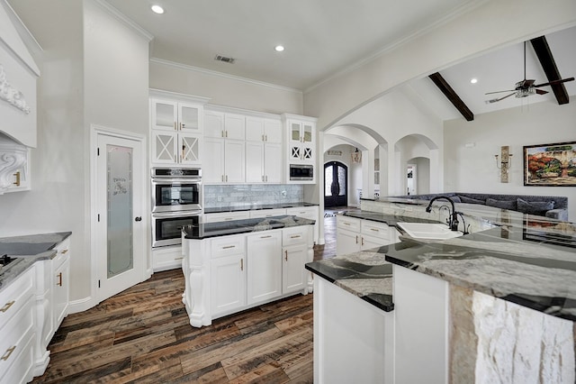 kitchen with ceiling fan, dark wood finished floors, appliances with stainless steel finishes, arched walkways, and a sink