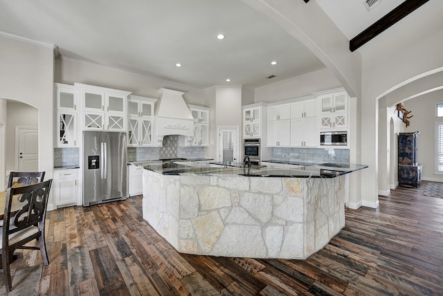 kitchen with white cabinetry, custom range hood, appliances with stainless steel finishes, and a spacious island