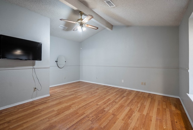 unfurnished living room featuring ceiling fan, light hardwood / wood-style floors, a textured ceiling, and vaulted ceiling with beams