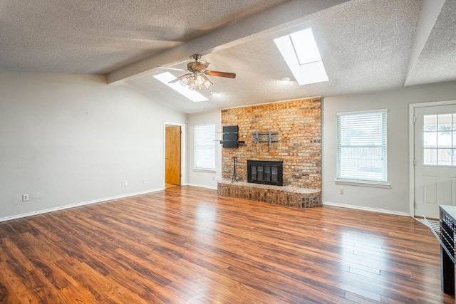 unfurnished living room featuring lofted ceiling with skylight, dark wood-type flooring, a textured ceiling, and a fireplace