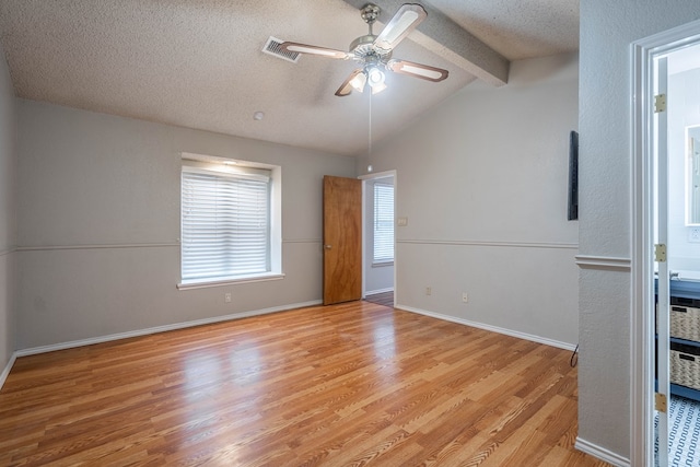 empty room featuring ceiling fan, light hardwood / wood-style floors, lofted ceiling with beams, and a textured ceiling