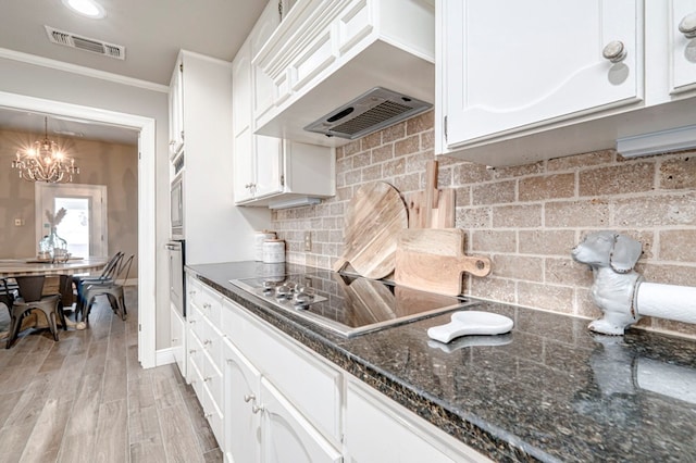 kitchen with black electric stovetop, a chandelier, oven, white cabinetry, and visible vents