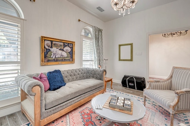 living area with baseboards, visible vents, wood finished floors, and a notable chandelier
