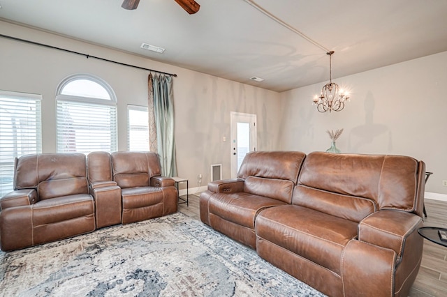 living area featuring wood finished floors, plenty of natural light, ceiling fan with notable chandelier, and baseboards