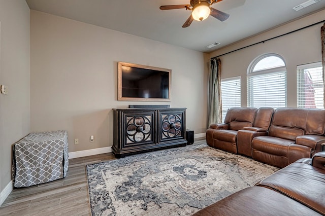 living room with wood finished floors, visible vents, a ceiling fan, and baseboards